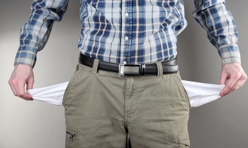 Man showing his empty pockets on grey background
