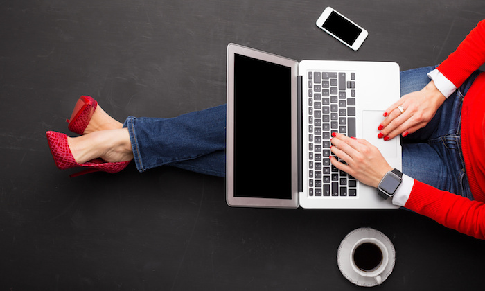 Woman sitting on ground at the office with computer in her lap