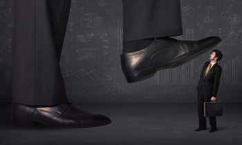 Huge leg stepping on a tiny businnessman concept