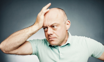 middle-aged man put his hand to his head complains, with shocked facial expression