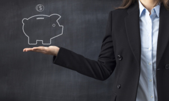 Holding piggy bank drawing front of blackboard