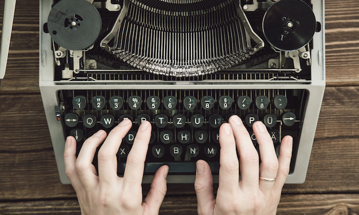 Writer typing with retro writing machine. View from above.