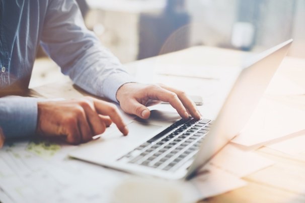 maos masculinas em laptop sob mesa de escritorio