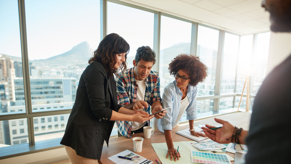 trio trabalhando em projetos sob mesa de escritório