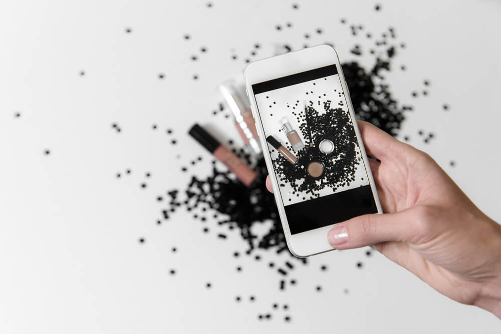 mao segurando smartphone ao tirar foto de produtos espalhados em mesa