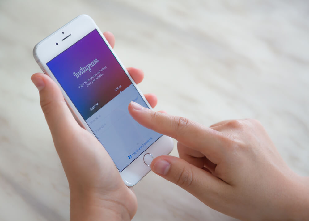 maos femininas segurando smartphone com tela de cadastro do aplicativo instagram