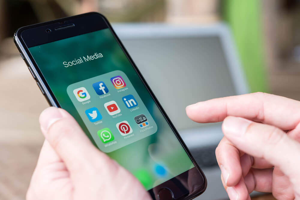 maos masculinas segurando smartphone com pasta de aplicativos de redes sociais em tela