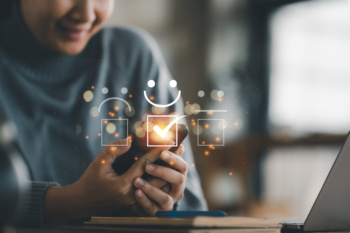 Customer service evaluation concept. smiling Asian female Is using a smartphone And she is pressing face emoticon smiling in satisfaction on virtual touch screen.