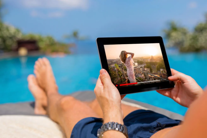homem sentado na praia segurando um tablet enquanto relaxa